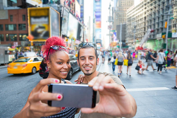 młoda para biorąc selfie na times square - new york city times square crowd people zdjęcia i obrazy z banku zdjęć