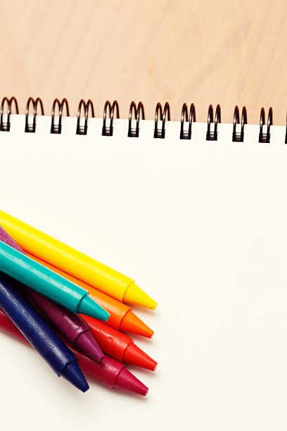 istock Clutch of bright crayons on spiral-bound sketchbook 516622273