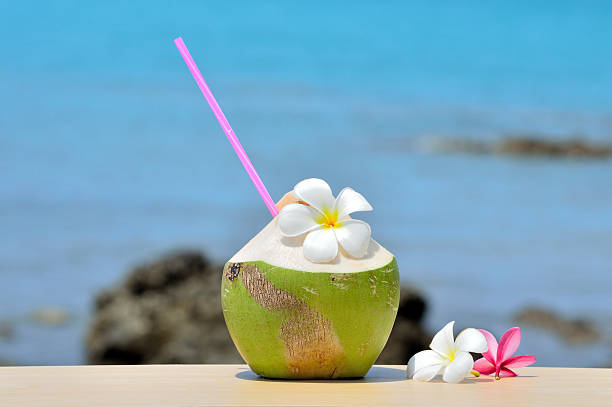 istock Coconut juice on wood table in blurred sea background 516625628