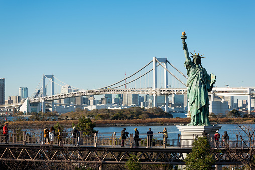Tokyo, Japan -December 18, 2056: Tourists at an elevated walkway in Odaiba enjoying the clear view of Tokyo Bay. The Statue of Liberty and the Rainbow Bridge in a view. 