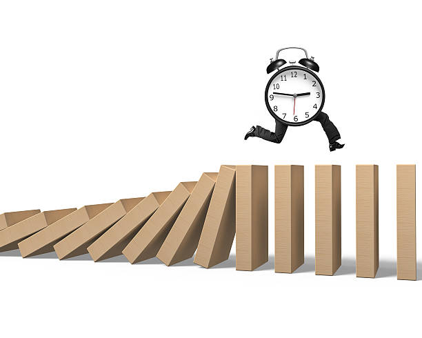 istock Alarm clock with human legs running on falling dominoes 516627564