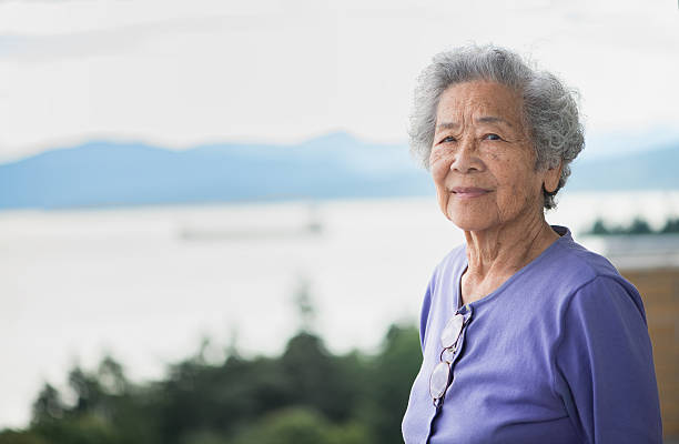 independent femme asiatique âgée profitant de vue à partir de appartement, vancouver, canada - octogénaire et plus photos et images de collection