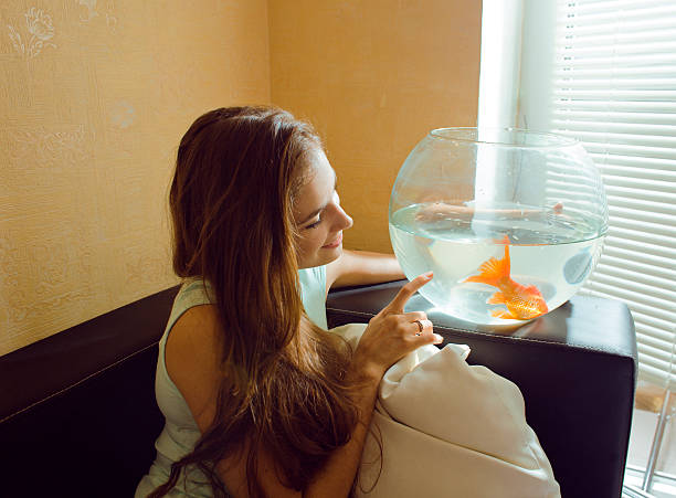 istock pretty woman playing with goldfish at home 516634529