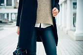 Close-up of a woman in a sweater, coat, black pants