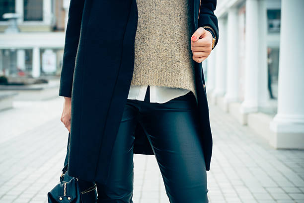 Close-up of a woman in a sweater, coat, black pants Details of women's clothing. Close-up of a woman in a sweater, coat, black pants. In her hand female bag. leggings stock pictures, royalty-free photos & images