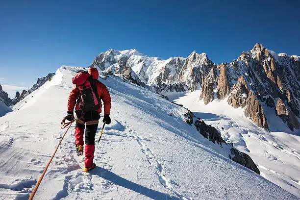 Mountaneer climbs a snowy ridge in Mont Blanc, France. Enterprise, diligence, team work: mountaneering concepts.