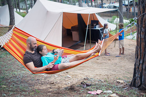 Relaxing in the camping Father with kids relaxing in the camping on holidays. hammock men lying down digital tablet stock pictures, royalty-free photos & images