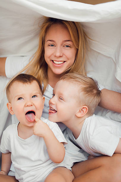 istock Two brothers playing with mother in bed 516653290