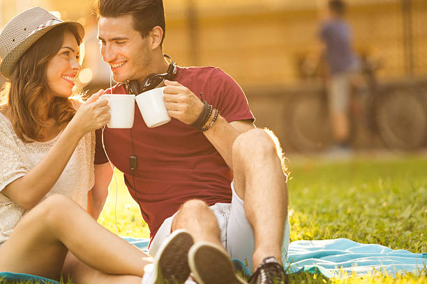 istock Happy young couple sitting in the park, drinking coffee 516655123