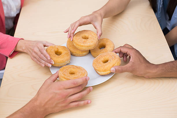 istock Business team reaching for doughnuts on table 516655153