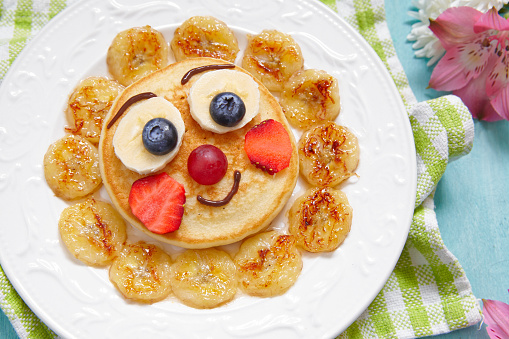 Funny breakfast pancakes with fruits for kids
