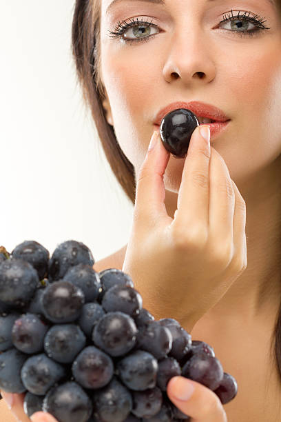 istock young beautiful woman eating grapes 516657899