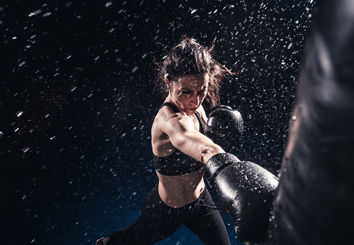 Young woman boxing at the punching bag