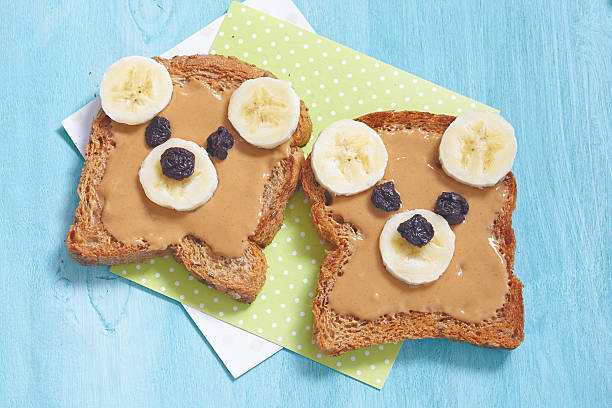 engraçado urso rosto sanduíche com pasta de amendoim, banana e uvas-passas - whole meal bread - fotografias e filmes do acervo