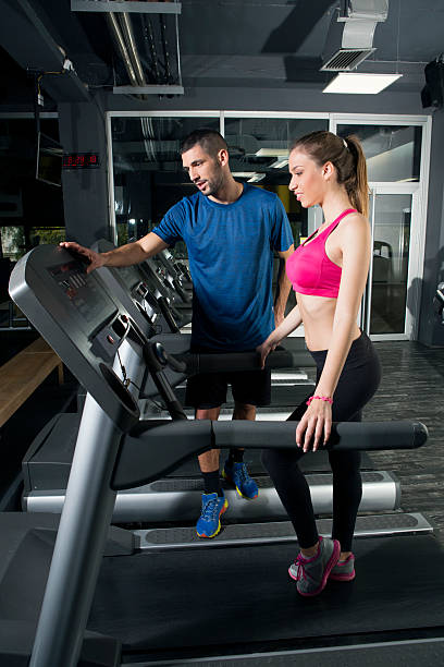 istock Young woman on treadmill, with instructor 516681910