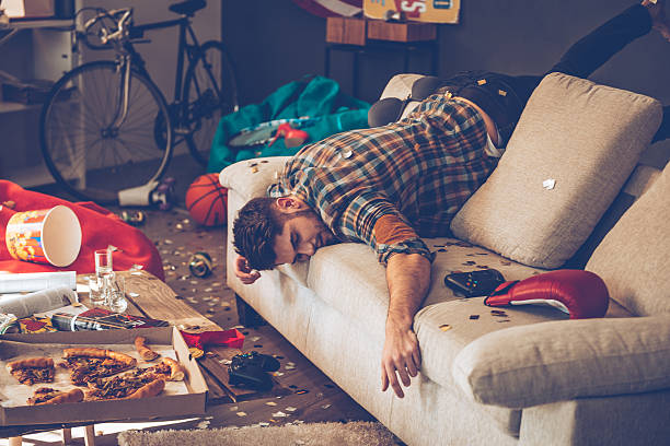 When the party is over. Young handsome man passed out on sofa in messy room after party drunk photos stock pictures, royalty-free photos & images