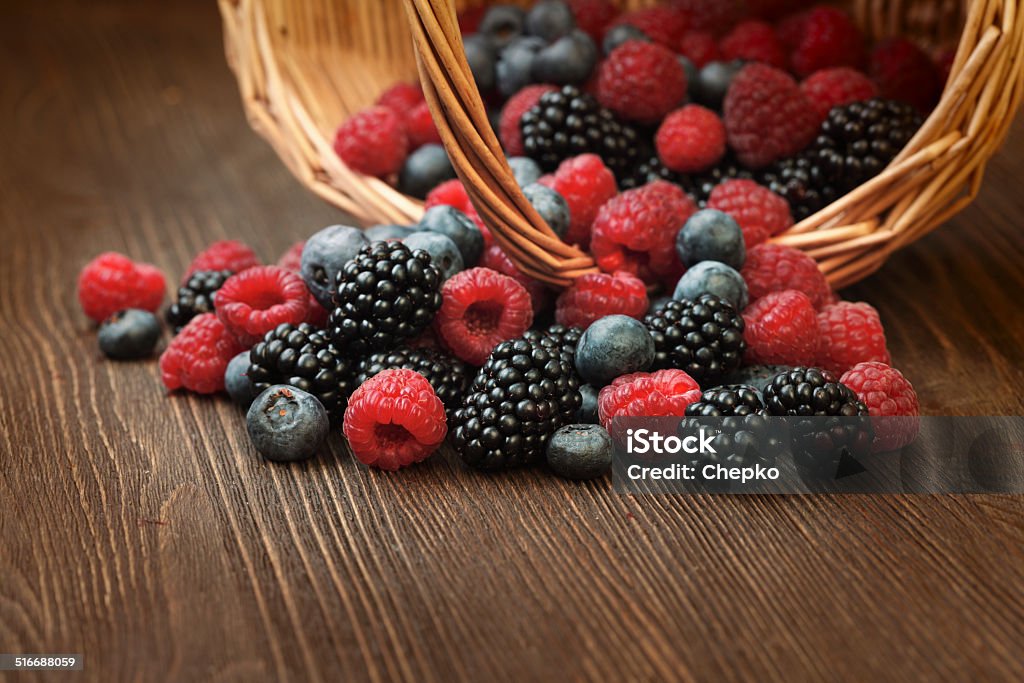 different berries  in a basket on a wooden table different berries (blueberries raspberries blackberries) in a basket on a wooden table Antioxidant Stock Photo