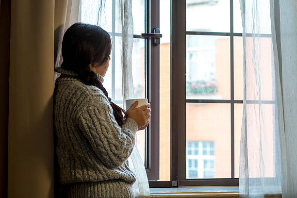 istock girl drinking coffee beside window,looking out of window 516690512