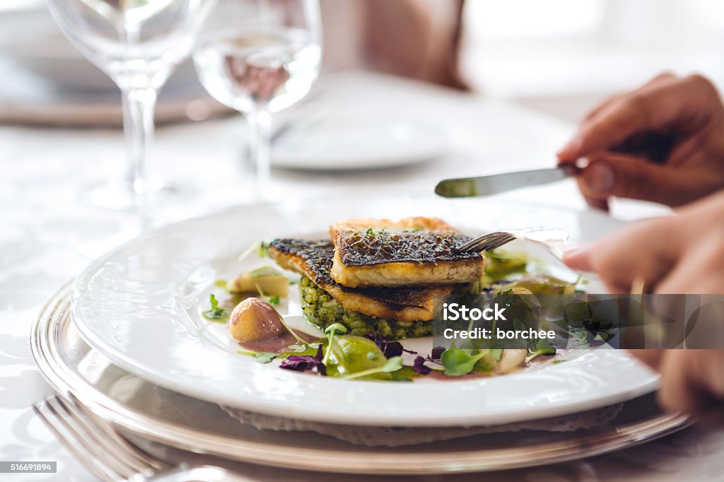 Uomo In un ristorante mangia pesce - Foto stock royalty-free di Gastronomico
