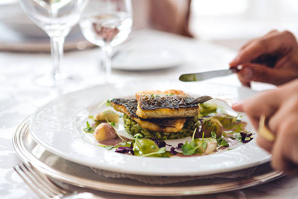 Man In Restaurant Eating Fish Man having dinner (grilled fish) in a restaurant. white restaurant dishes stock pictures, royalty-free photos & images
