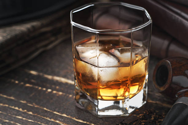 istock Whiskey with ice and pipe on the wooden table 516694744