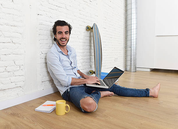 istock young man hipster style sitting on floor working on laptop 516715156