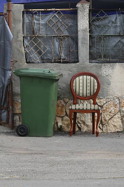 Trash Can next to a Padded Chair on the Sidewalk