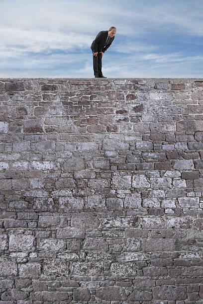 istock Businessman Looking Down from the High Stone Wall 516719258