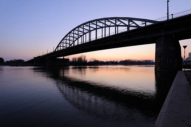 John Frost Bridge over Lower Rhine at Arnhem after sunset The John Frost Bridge (John Frostbrug in Dutch) is the road bridge over the Lower Rhine at Arnhem, in the Netherlands. The bridge is named after Major-General John Dutton Frost (1912–1993), who commanded the British forces that reached and defended the bridge during the Battle of Arnhem in September 1944. The bridge was featured in the 1977 film A Bridge Too Far, although a different bridge was used for the film. arnhem photos stock pictures, royalty-free photos & images