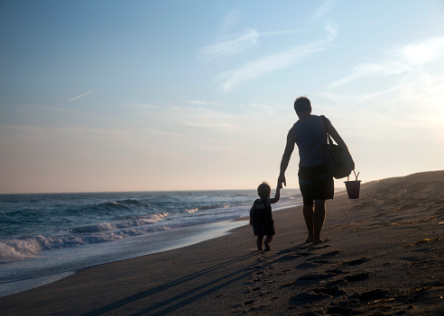 Silhouette of father and little daughter on sunset -