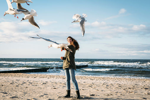 young woman plays with seagulls at the baltic
