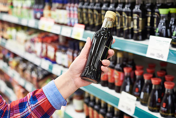 Buyer with soy sauce in store Buyer with the soy sauce in a store soia sauce stock pictures, royalty-free photos & images