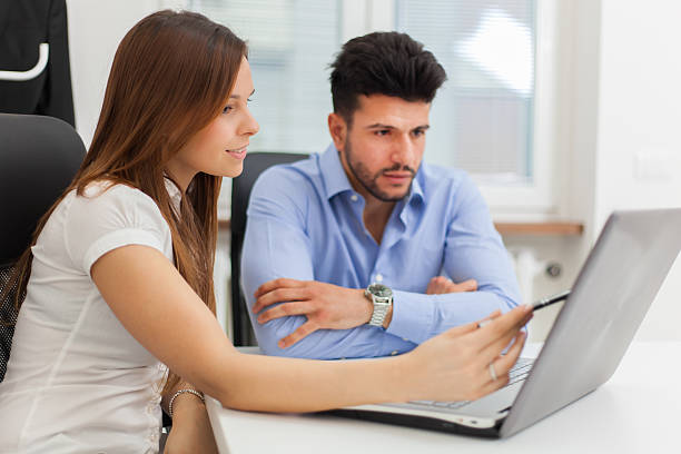 istock Smiling business people using a laptop computer in their office 516725618