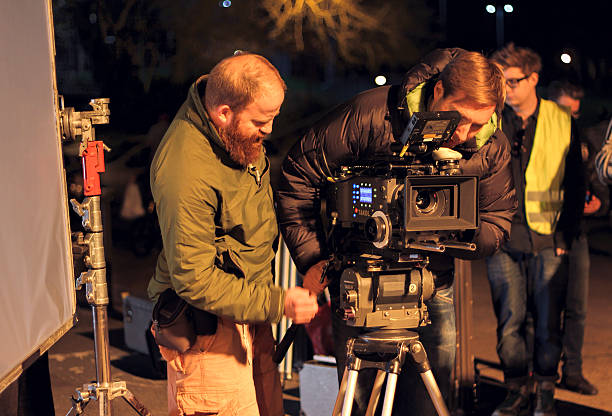 Film crew on location, night shoot. Cinamatographer with 4k camera London, UK - March 30, 2012:  Film Crew On Location Night Shoot. DoP and assistant preparing to shoot using 4k camera. tv production stock pictures, royalty-free photos & images