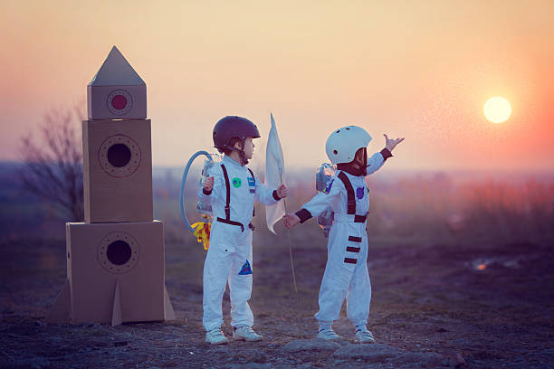 Two adorable children, playing in park on sunset Two adorable children, boy brothers, playing in park on sunset, dressed like astronauts, imagining they are flying on the moon model rocket stock pictures, royalty-free photos & images