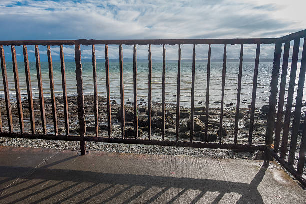 Looking through a rusted fence at the shoreline in West Seattle, Washington.