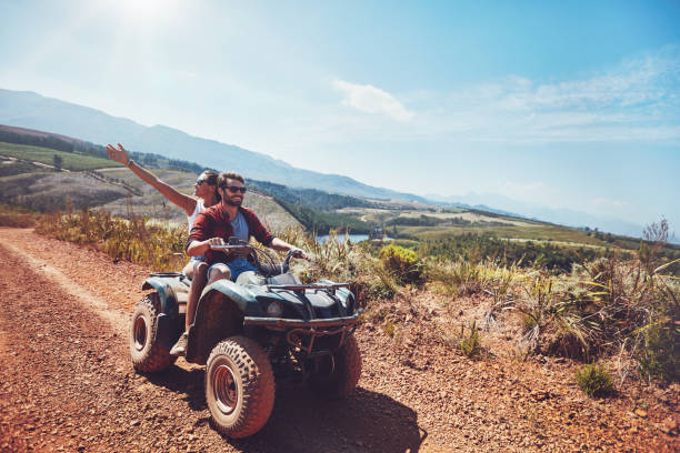 Couple on an off road adventure Young couple on an off road adventure. Man driving quad bike with girlfriend sitting behind and enjoying the ride in nature. quadbike stock pictures, royalty-free photos & images