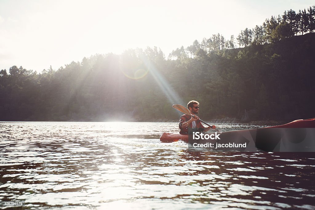 Man paddling kayak on a summer day Young man canoeing in a lake. Man paddling kayak on a summer day. Active Lifestyle Stock Photo
