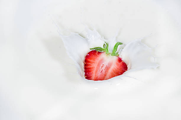 istock Strawberry falling into splashing milk. Isolated on white. 516757458