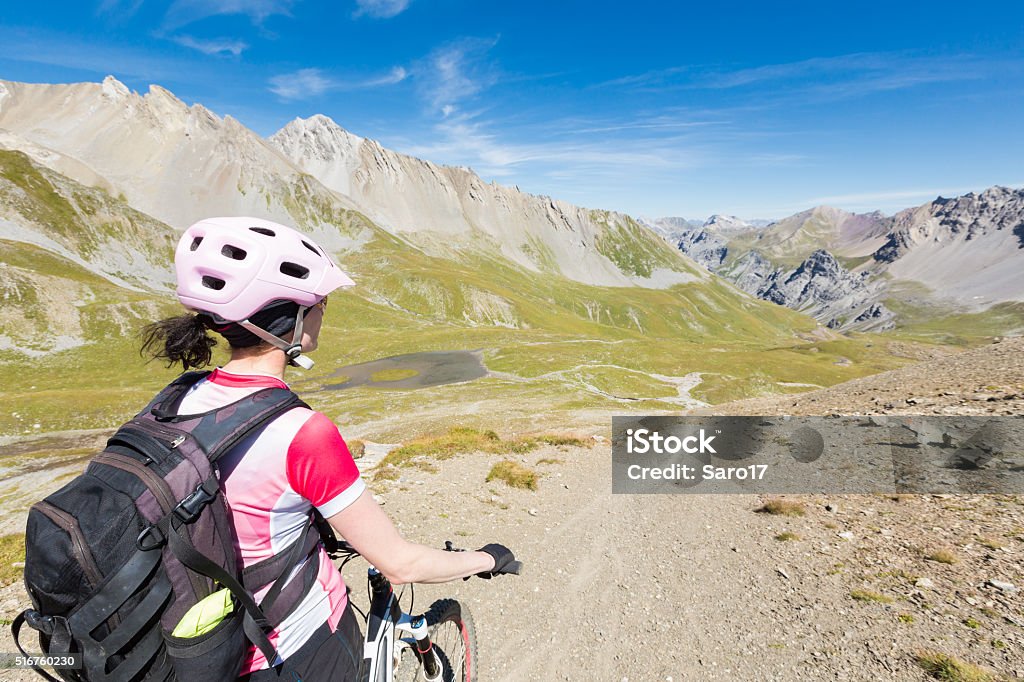 Overlooking Welschtobel, Switzerland A female mountainbiker is overlooking  at an altitude of 2573 mt (8442 ft.) the so called Welschtobel before starting the downhill towards the City of Arosa, a wellknown Resort in the Graubünden Mountains, Switzerland. Cirrus Stock Photo