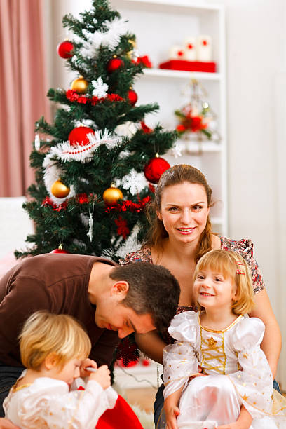 istock parents with two daughters spending time near christmas tree 516761618