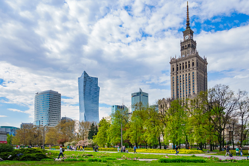 Warsaw, Poland - April 22, 2014: People walk in a park at the Palace of Culture and Science with skyscrapers in the background in downtown Warsaw, Poland.