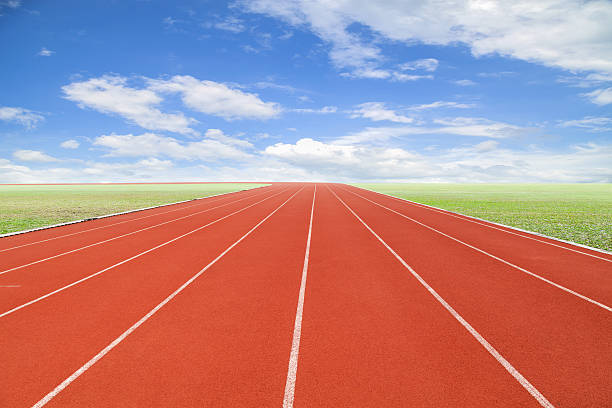 istock Running track with green grass and blue sky white cloud. 516764158