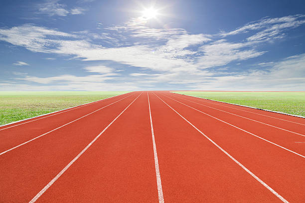 istock Running track with green grass and blue sky white cloud. 516764814