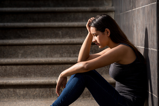 Sad teenage girl with depression sitting on stairway
