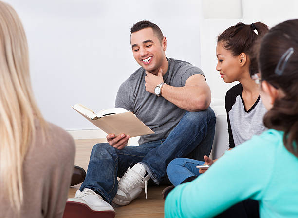 istock Group of college students reading book on floor 516779733