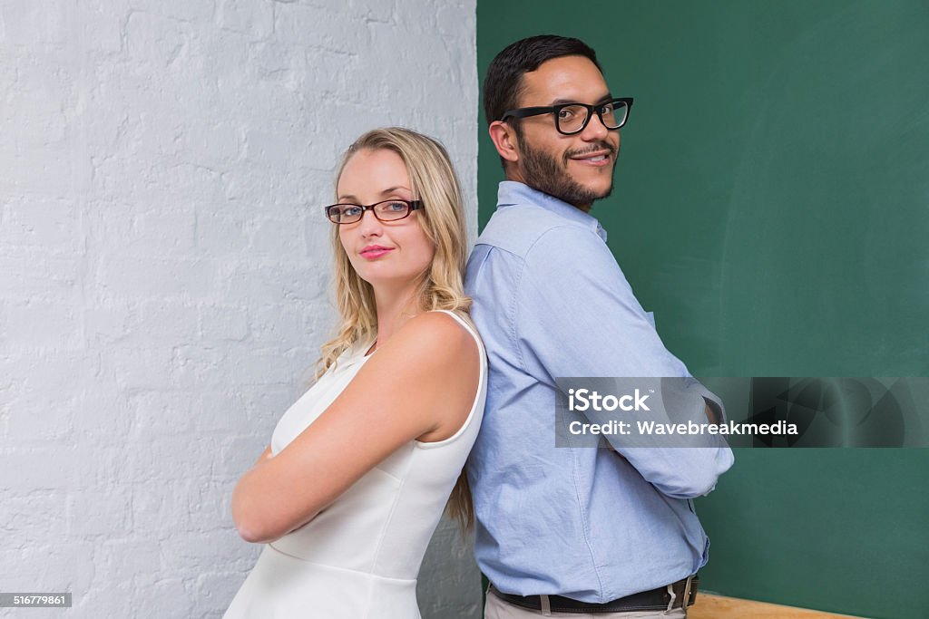 Confident business people with arms crossed Portrait of two confident young business people with arms crossed in office Back To Back Stock Photo