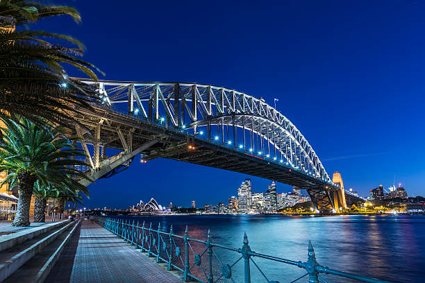 sydney harbour bridge und die skyline der stadt beleuchtet bei dämmerung, australien - sydney australia australia sydney opera house skyline stock-fotos und bilder