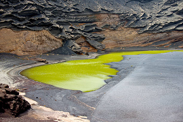 istock Green lagoon inside black rough volcano crater 516788506