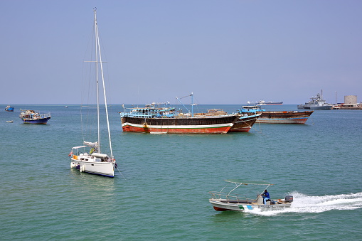 Port of Djibouti, Republic of Djibouti - February 8, 2016: Coast Guard boat goes by luxury sailing boat, fishing and cargo ships at anchor in the port of Djibouti